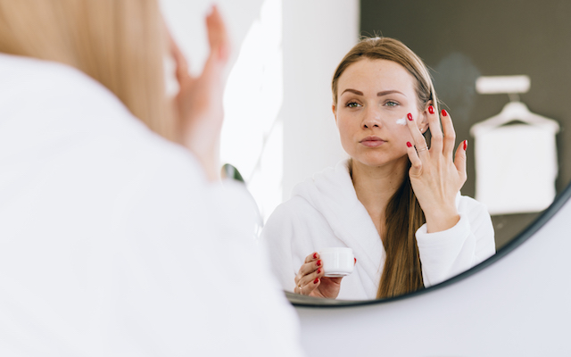 Woman applying moisturizer to her skin.