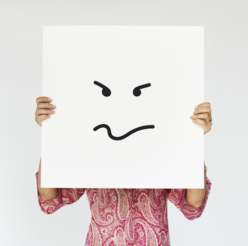 Woman holding up an angry face drawing in front of her face.