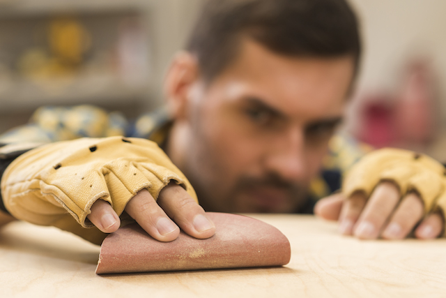 man holding sandpaper and buffing.