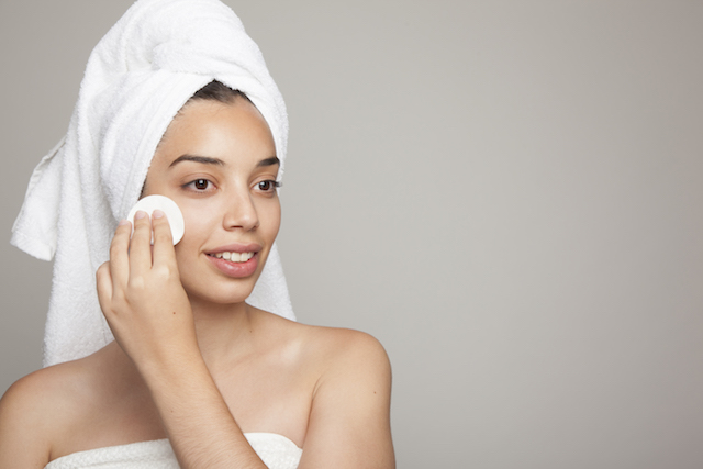 Woman applying micellar face wash with a cotton pad.