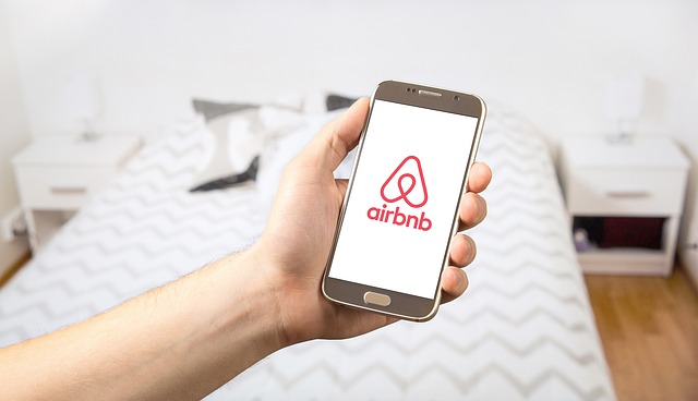 person holding mobile phone with airbnb app.