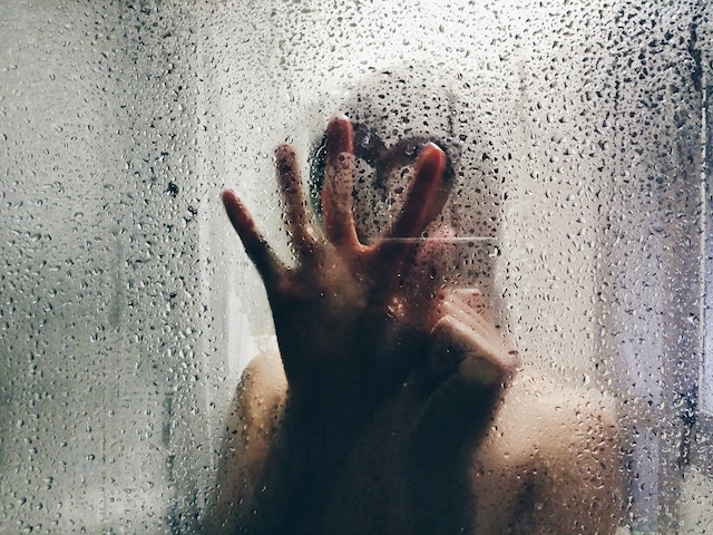 woman making heart in the shower door.