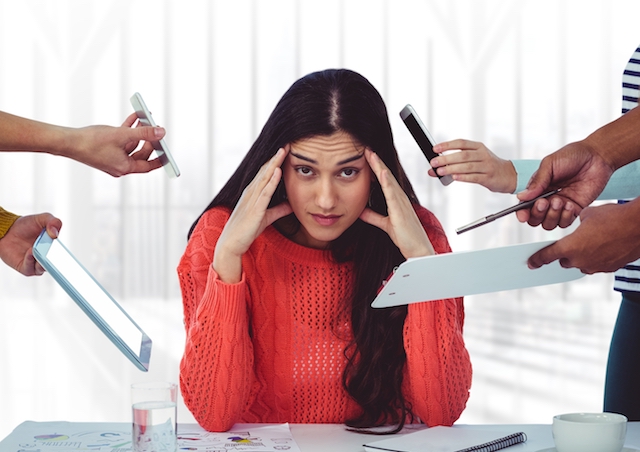 woman holding head, stressed sitting in an office.