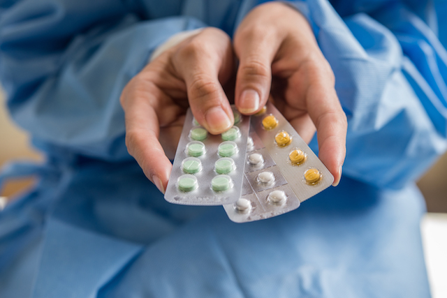 woman holding different types of birth control pills. 
