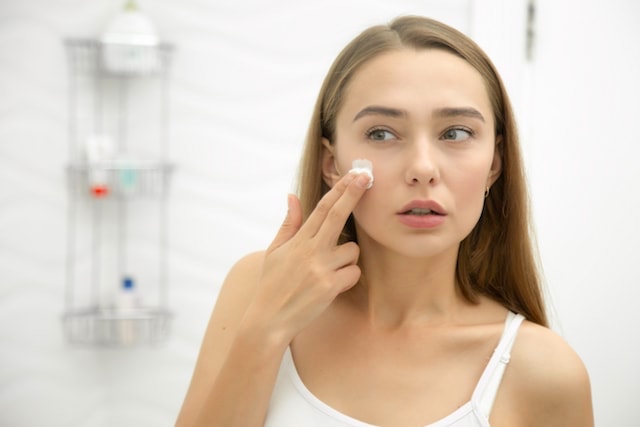 woman applying a topical acne treatment to her face. 