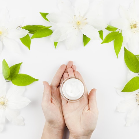 Hands holding a jar of eye moisturizer.