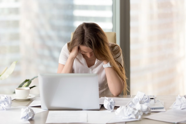 a woman that appears stressed in her office. 