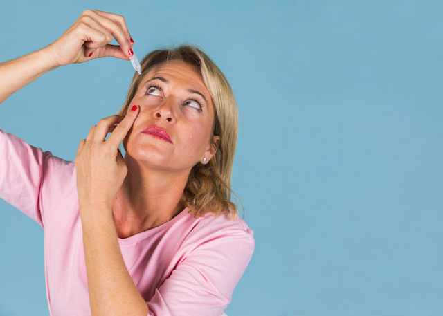 woman putting in eye drops.