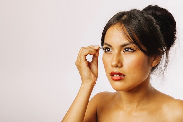 Woman who is tweezing her eyebrows, the easiest task for busy women.