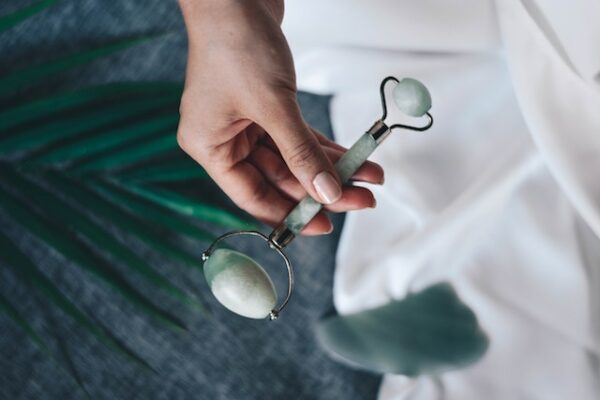 a woman holding one version of jade rollers.