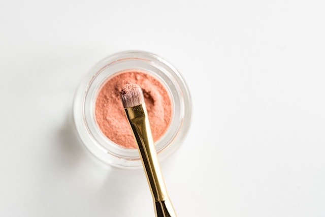 A jar of cream eyeshadow with makeup brush.