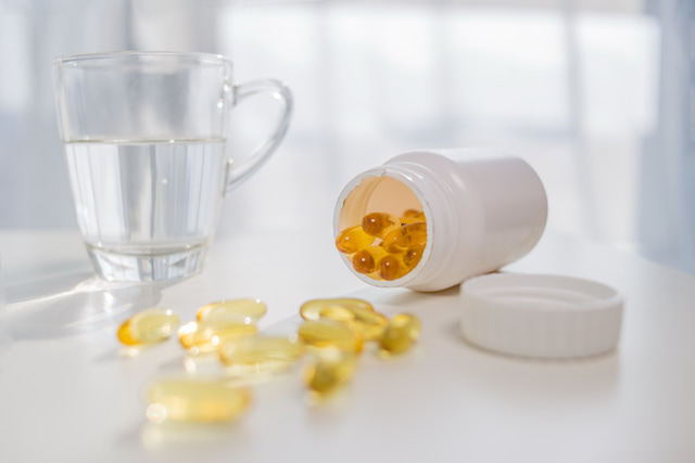 a jar of supplements like biotin with a glass of water.