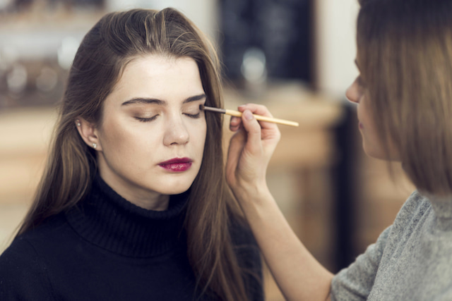 woman having eye makeup applied to lid over concealer.