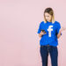 woman looking at her phone, upset, wearing a facebook shirt. probably the result of soft ghosting.