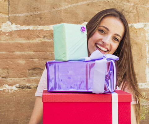 a happy woman holding many wrapped gifts.