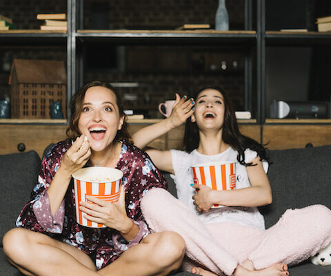 two women having fun watching a movie for a girls' night in.