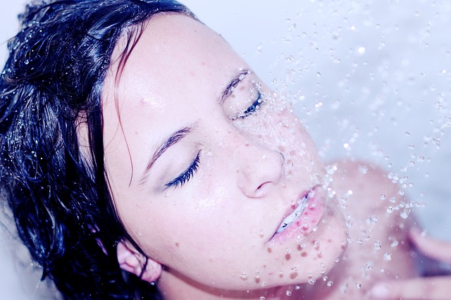 Woman's face under a shower head to clear out her sinuses. 