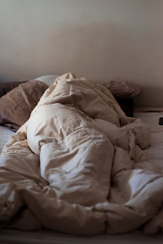 Mujer tumbada en la cama tapada hasta arriba